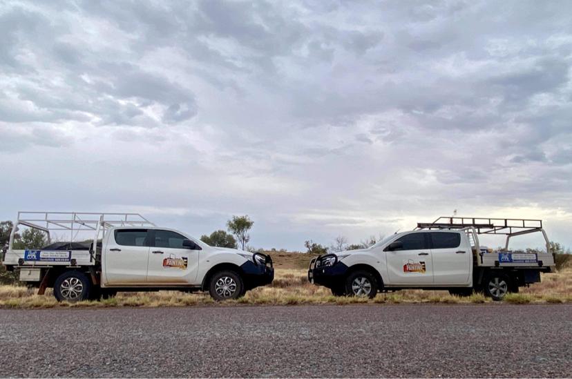 Two white North West Queensland Painting trucks parked on the side of the road